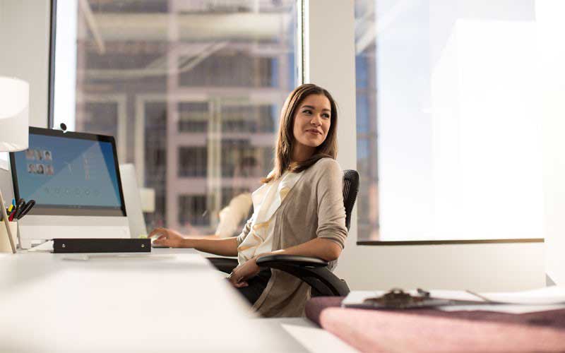 Young woman at desk with laptop reclining in her chair.