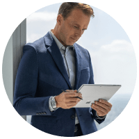 man in suit standing near office window holding a surface tablet device