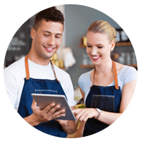 Two smiling small business owners look at tablet in cafe