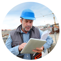 Male and female construction worker looking at laptop at construction site.