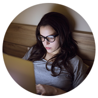 Woman using laptop computer in hotel bedroom at night