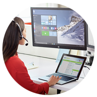 Woman on headset works on laptop and desktop computer