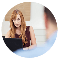 Business woman in working on laptop computer with businessman in foreground