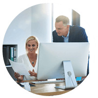 Business professionals look over data in front of desktop computer