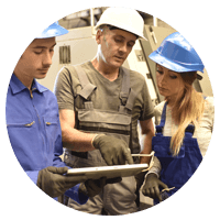 Three hard hatted manufacturers looking a tablet.