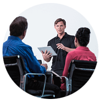 Man leading a meeting with teammates while holding a tablet