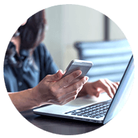 Business woman checking email on smart phone while using notebook computer