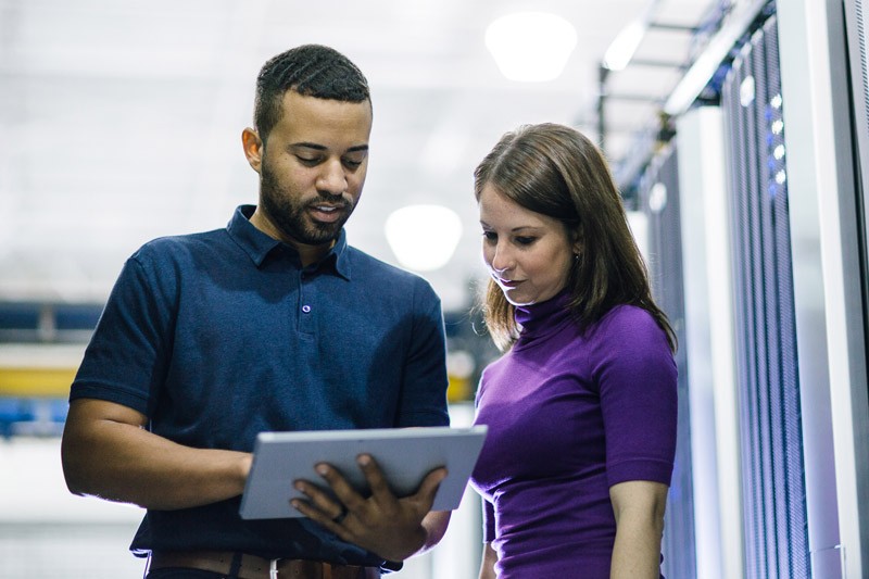 Business manager discusses IT solutions using tablet computer in data center.