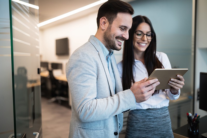 IT executives working together on a tablet device solving problems  