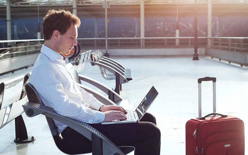 man with luggage using laptop