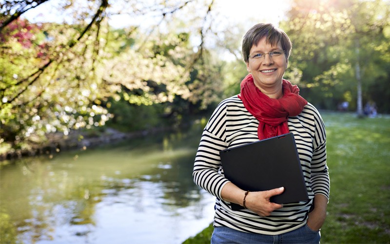 Smiling woman holding Microsoft device outdoors