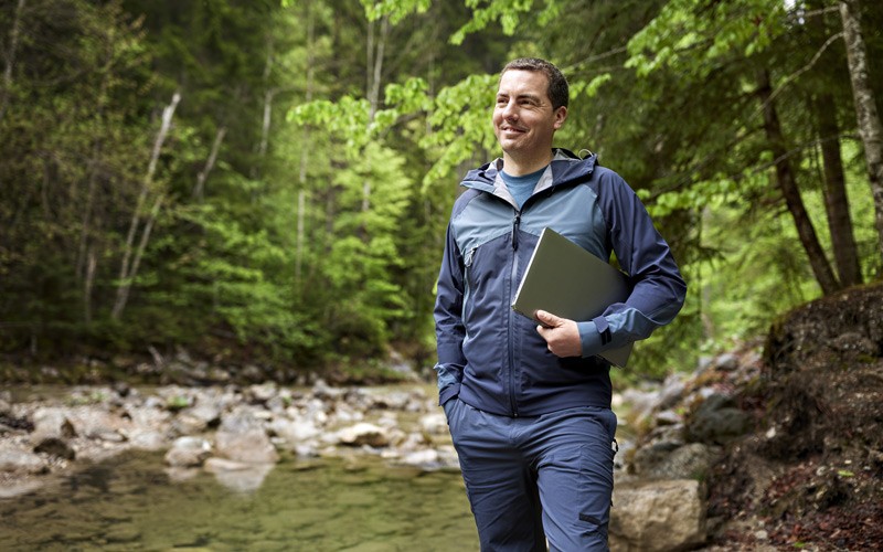 Smiling man holding Microsoft device outdoors