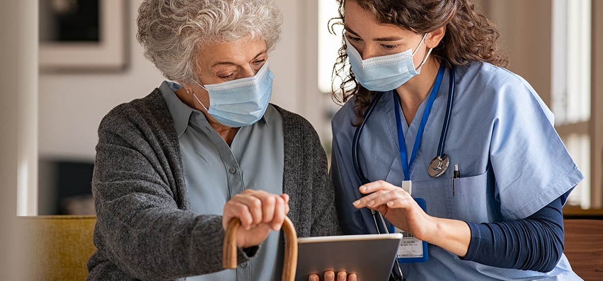 Senior woman and nurse using digital tablet at home during consult