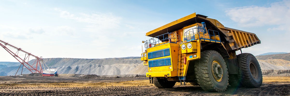 Mining vehicle on dirt planes with mountains in the background