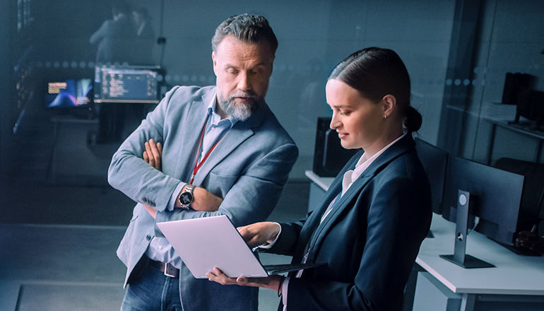 woman showing laptop to male colleague