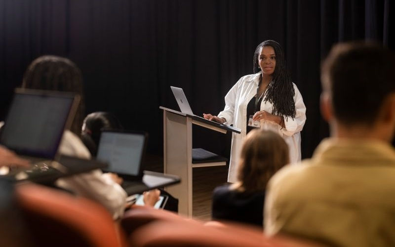 woman presenting on podium using mac