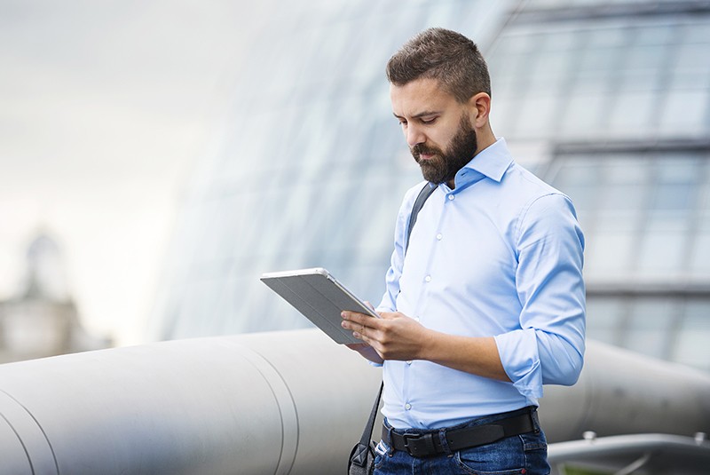 Businessman using DocuSign electronic signature software on tablet computer while walking across bridge