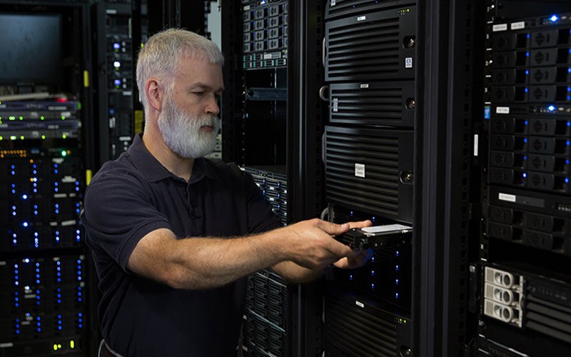 Adding backup on your data storage IT professional inserting disk on data storage