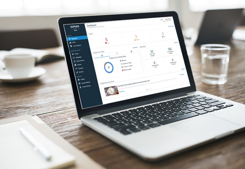 Sophos Central Management Dashboard displayed on notebook computer on wood desk in office