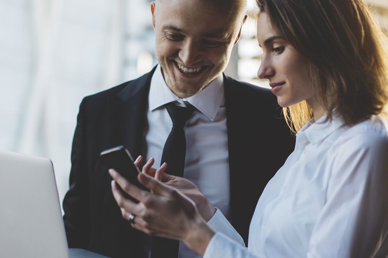 Business man and woman looking at content on smart phone.