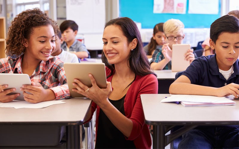 Teacher using tablet device with students