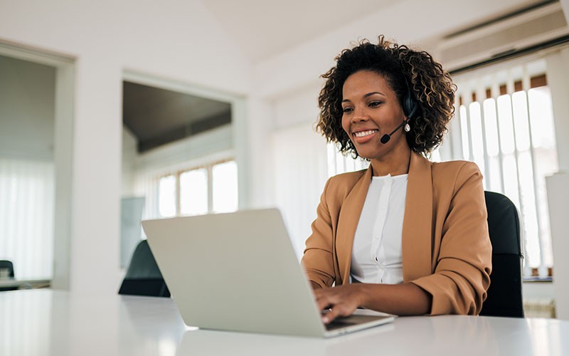 Help desk support technician with headset on laptop computer