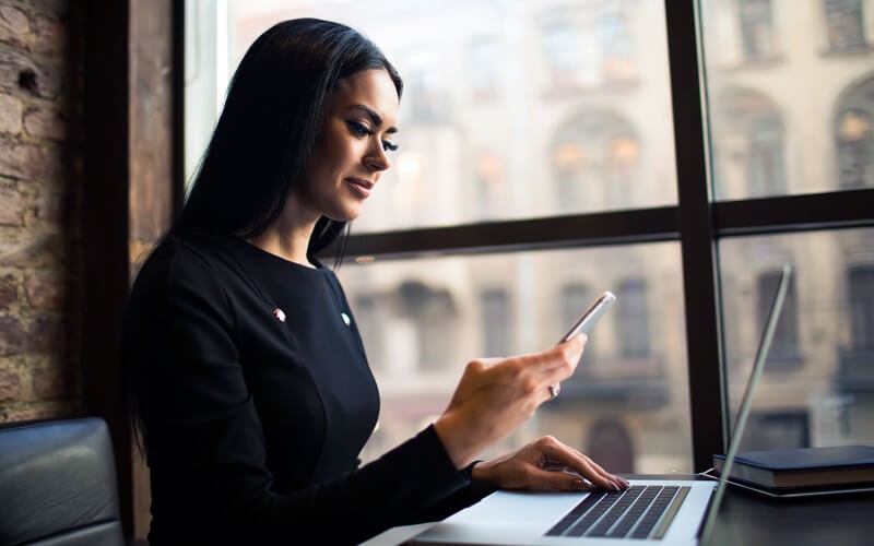 Government official using mobile device and laptop in front of window