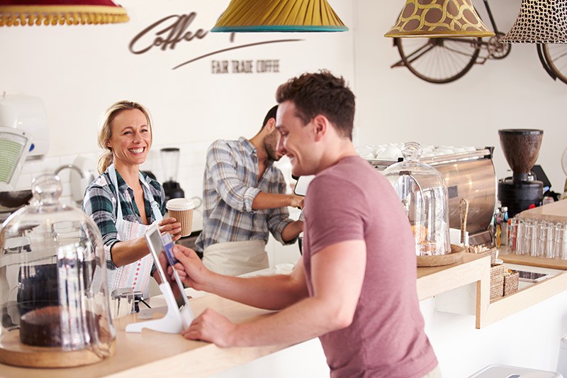 Smiling cafe worker rings up customer