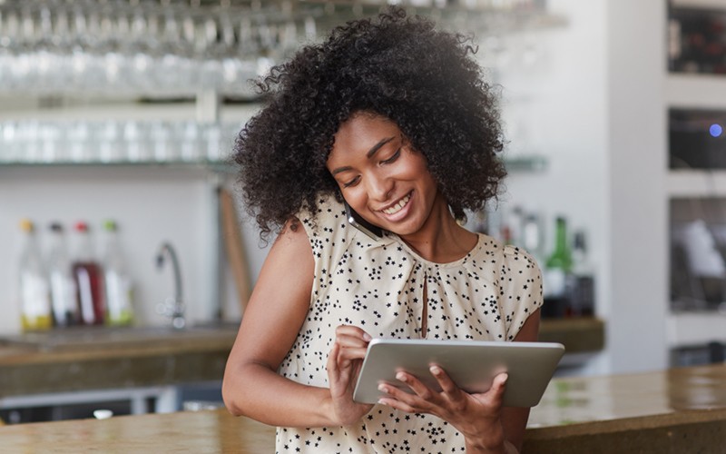 Smiling small business owner on phone and tablet