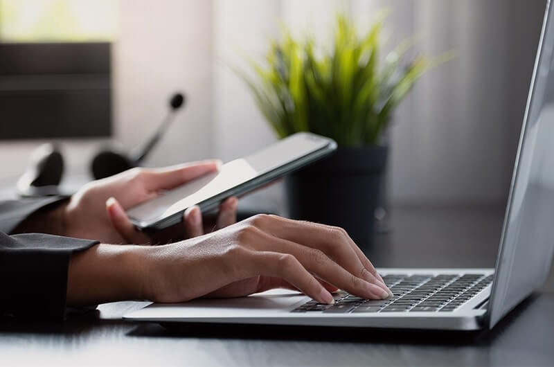 Close up of hands on laptop and smart device