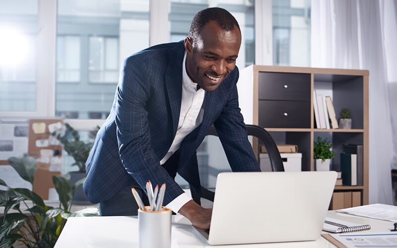 Close up of laptop computer sitting on table with people surrounding it