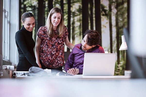 two-women-man-laptop-discussion-at-desk