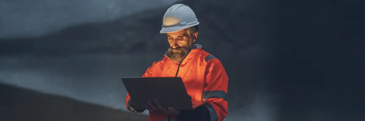 Engineer inspects mine using laptop with AI analytics, monitoring structural integrity.