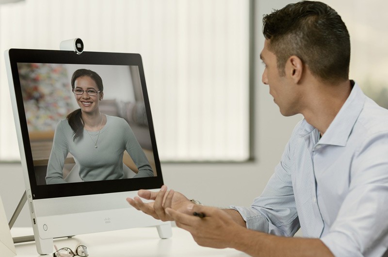 Businessman sittling at his desk videoconferences with teammate.