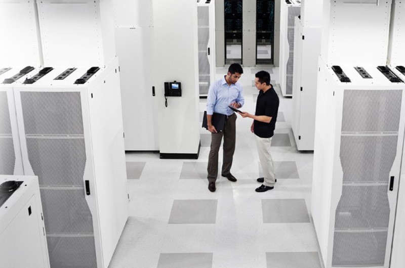 IT admin near server rack on tablet computer