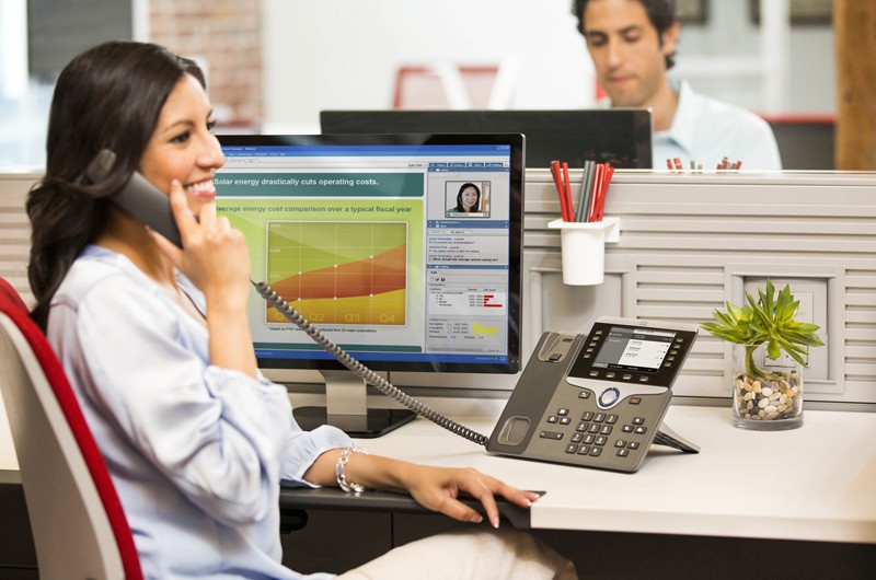 Woman in white coat at her desk on the phone.