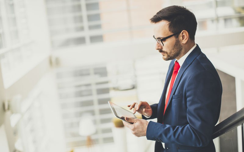 Business man walking through building using tablet device