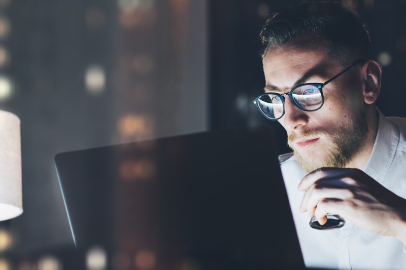 Business man with glasses working late in office looking at laptop