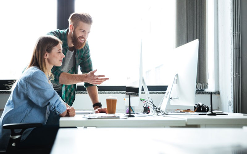 Two employees looking at monitor