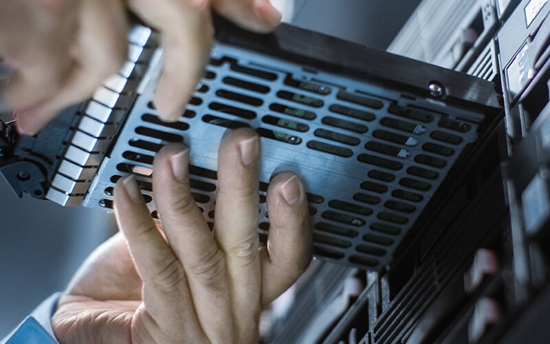 IT engineer installing new hard drive to server rack
