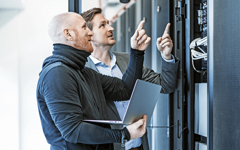 Two IT engineers on laptop working in data center