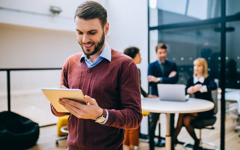 smiling-man-on-tablet-device-in-office