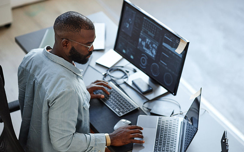 male-working-on-monitor-and-laptop-gi-1435220822