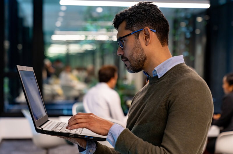 Homme d’affaires avec ordinateur portable debout dans un bureau