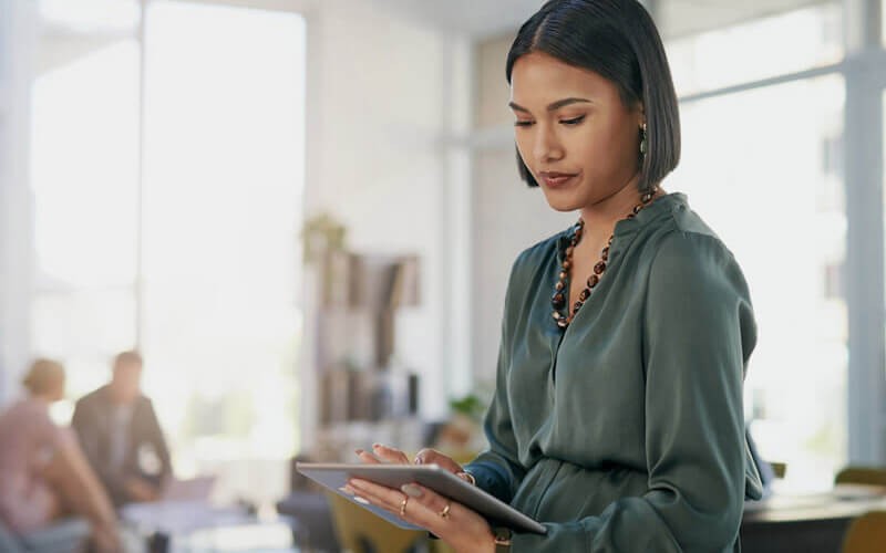 Maintain compliance, so you can focus on serving your customers and innovating. Businesswoman on tablet in modern office