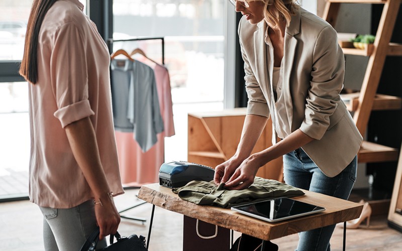 Small business owner of clothing store rings up customer