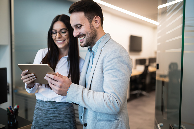 Deux professionnels souriant devant une tablette électronique