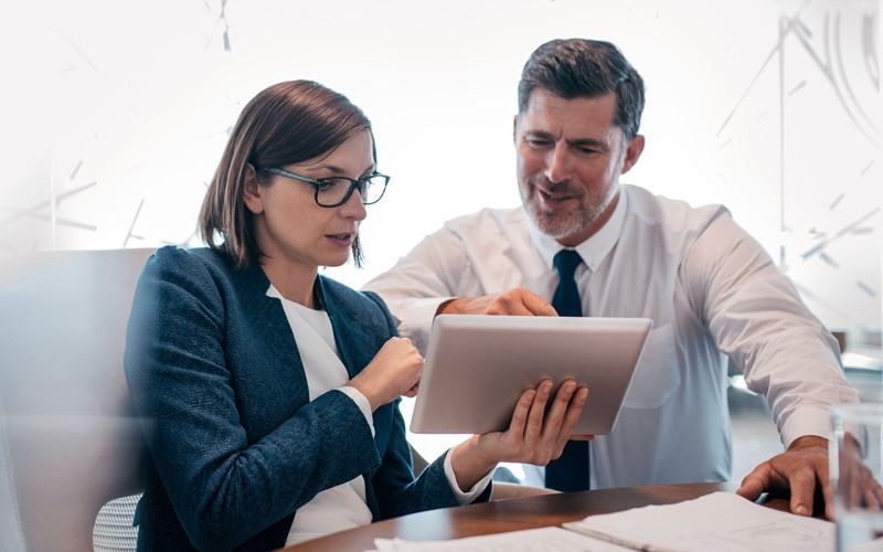 Business manager talks with employee using tablet computer