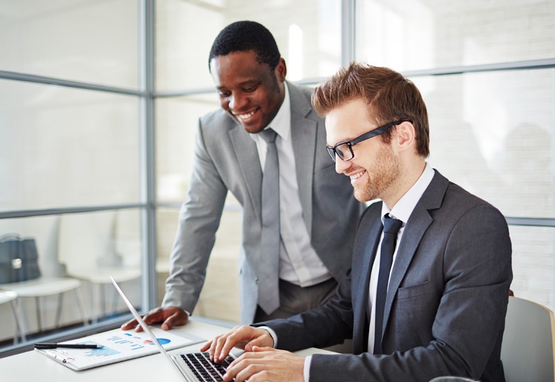 Two businessmen look over laptop computer