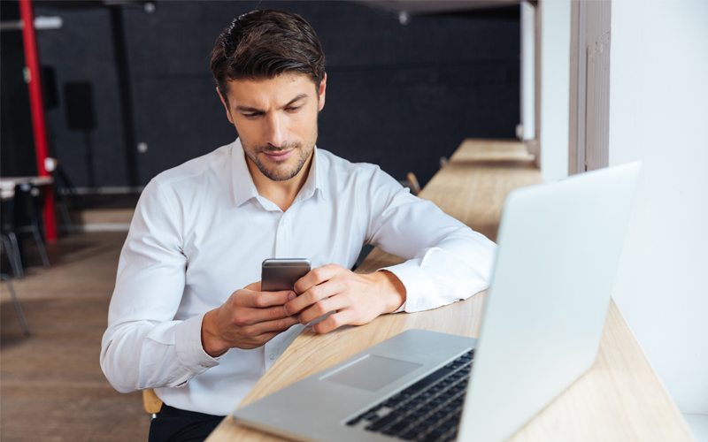 Businessman reviewing orders on laptop computer and phone